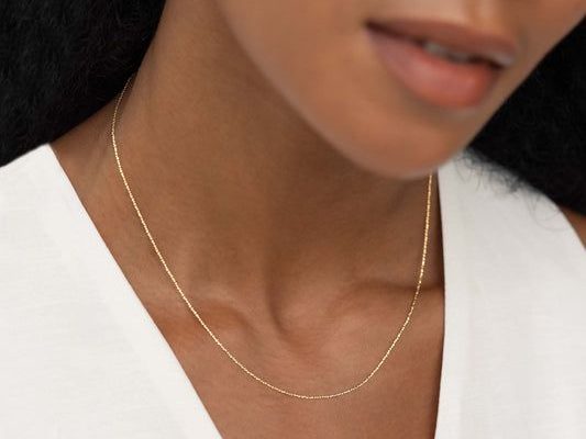 Närbild på en kvinna som bär ett elegant bismarckhalsband i guld.
