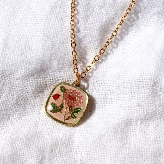 Guldhalsband med ett kvadratiskt emaljhänge föreställande blommor.